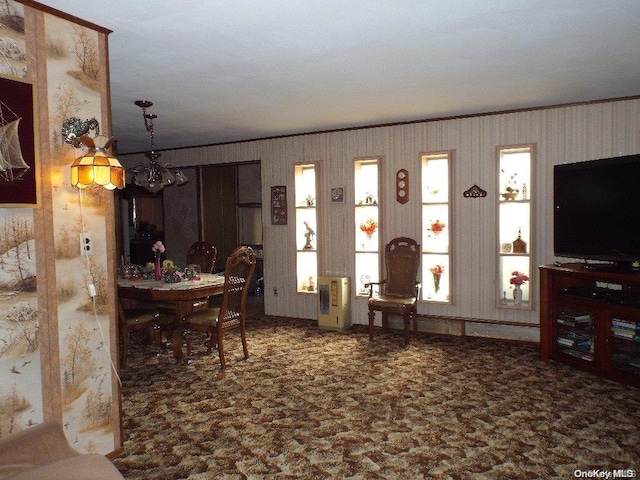 living room with heating unit, ornamental molding, and a notable chandelier