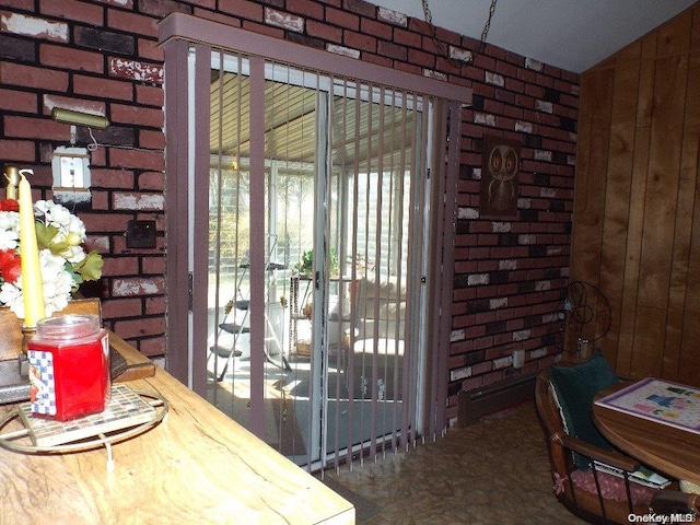 doorway to outside featuring brick wall and vaulted ceiling