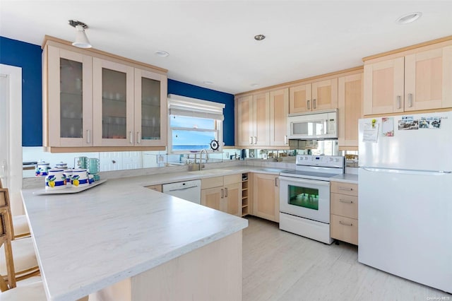 kitchen featuring sink, light hardwood / wood-style flooring, kitchen peninsula, white appliances, and light brown cabinetry