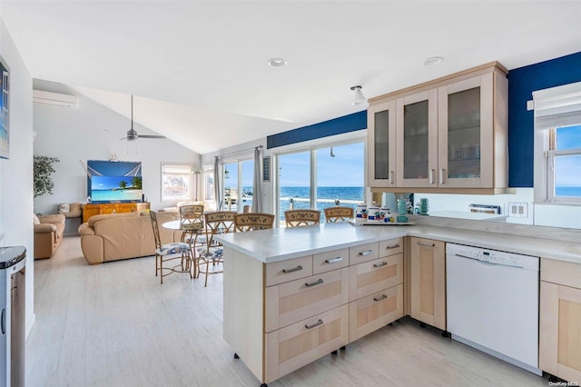 kitchen with light hardwood / wood-style flooring, kitchen peninsula, white dishwasher, lofted ceiling, and light brown cabinetry