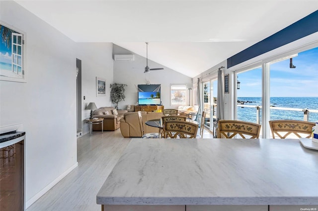 kitchen with an AC wall unit, vaulted ceiling, ceiling fan, light hardwood / wood-style floors, and beverage cooler