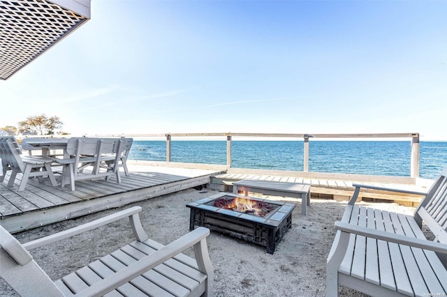 view of patio featuring a fire pit, a deck with water view, and a view of the beach