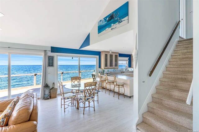 dining room with a water view, high vaulted ceiling, and light hardwood / wood-style floors