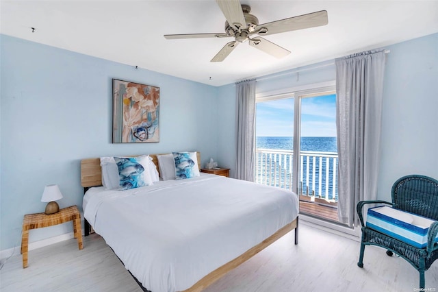 bedroom with ceiling fan, light hardwood / wood-style floors, and a water view