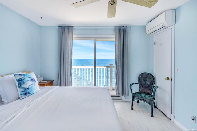 bedroom featuring a wall mounted air conditioner, ceiling fan, a water view, and light hardwood / wood-style flooring