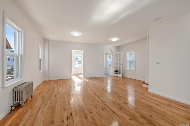 spare room with radiator heating unit and light hardwood / wood-style flooring