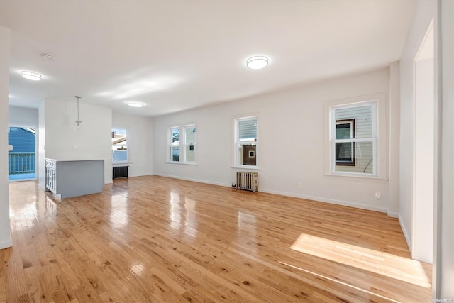 unfurnished living room with light wood-type flooring and radiator heating unit