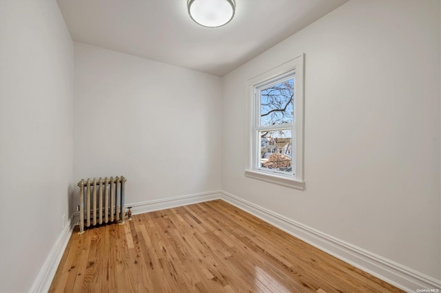 spare room with radiator heating unit and light hardwood / wood-style floors