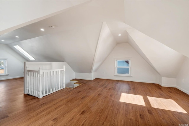 additional living space featuring wood-type flooring and lofted ceiling with skylight