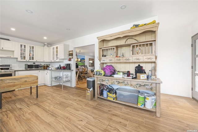4 Maple St, Glenwood Landing, NY 11547 - kitchen featuring appliances with stainless steel finishes, light wood-style floors, tasteful backsplash, glass insert cabinets, and recessed lighting