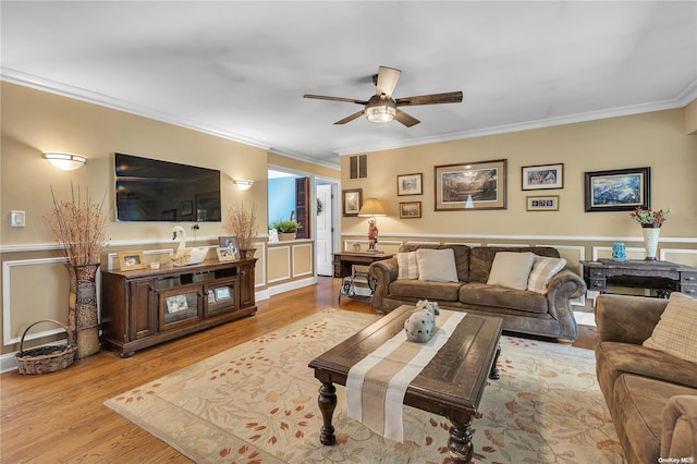 living room featuring ceiling fan, ornamental molding, and light wood-type flooring