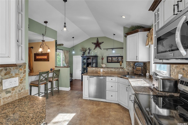 kitchen with appliances with stainless steel finishes, decorative light fixtures, white cabinetry, and plenty of natural light