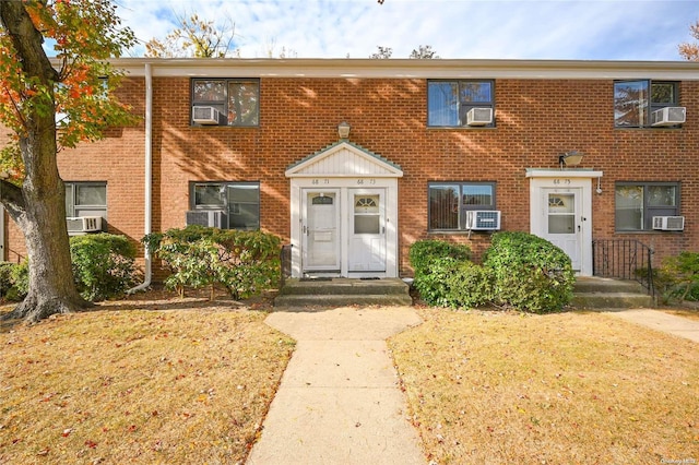 view of property featuring a front lawn and cooling unit