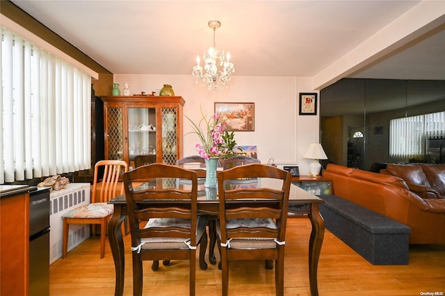 dining space featuring radiator heating unit, light hardwood / wood-style floors, and an inviting chandelier