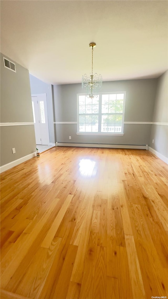 unfurnished dining area with light hardwood / wood-style floors, a baseboard heating unit, and a chandelier