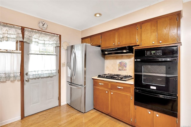 kitchen featuring light hardwood / wood-style floors, ornamental molding, appliances with stainless steel finishes, and tasteful backsplash