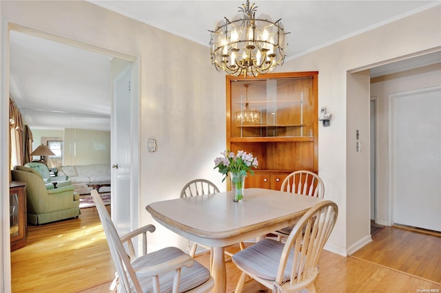 dining area with light hardwood / wood-style floors, a notable chandelier, and ornamental molding