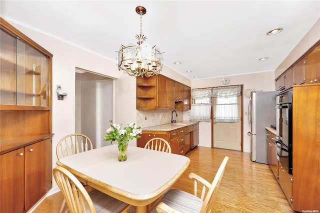 dining room with crown molding, sink, a chandelier, and light wood-type flooring