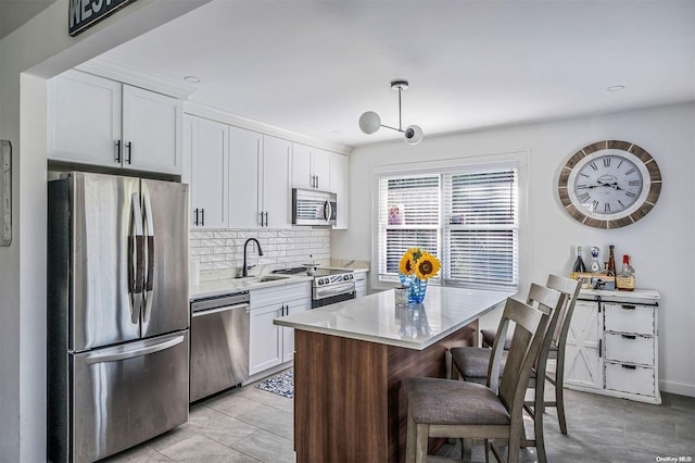 kitchen featuring a center island, sink, decorative backsplash, appliances with stainless steel finishes, and white cabinetry