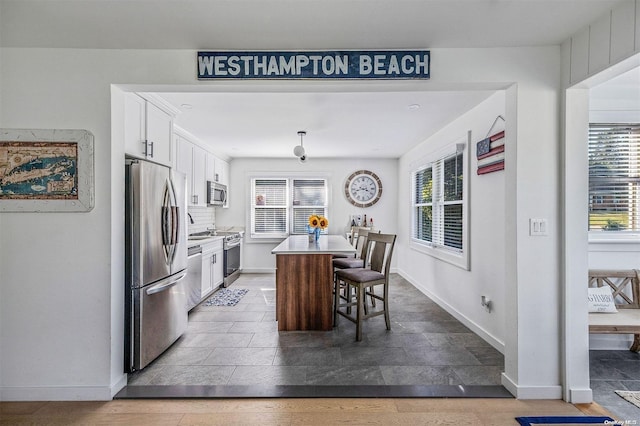 kitchen with white cabinets, a kitchen breakfast bar, stainless steel appliances, and a kitchen island