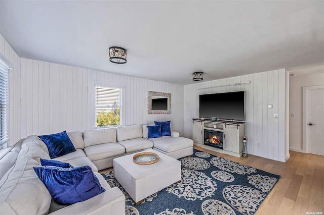 living room with light hardwood / wood-style floors and wood walls