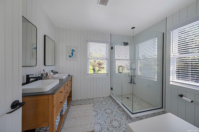 bathroom with vanity, wooden walls, a wealth of natural light, and a shower with shower door