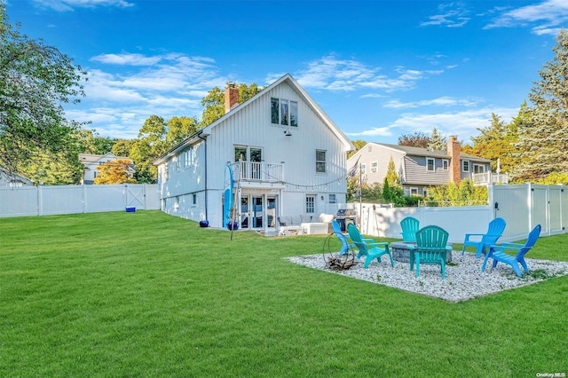 back of property with a patio area, a yard, a balcony, and an outdoor fire pit