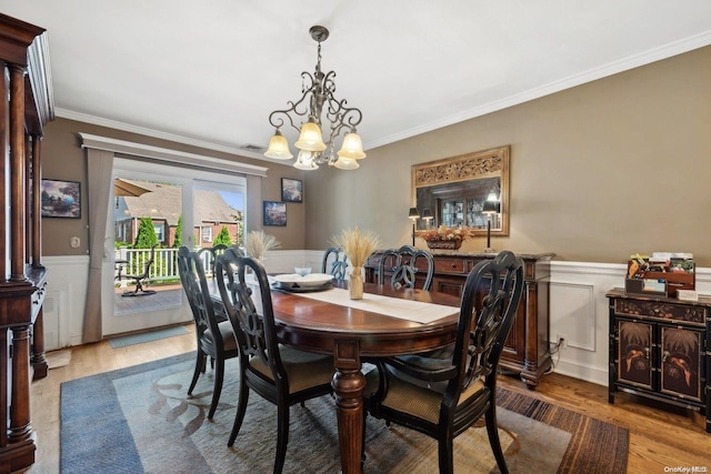 dining room featuring wood-type flooring, crown molding, and a notable chandelier