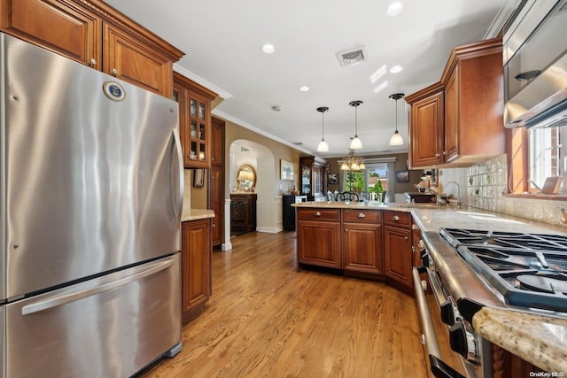 kitchen with light hardwood / wood-style flooring, a healthy amount of sunlight, decorative light fixtures, and appliances with stainless steel finishes