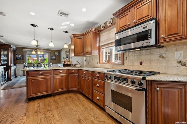 kitchen featuring kitchen peninsula, stainless steel appliances, a wealth of natural light, and light hardwood / wood-style floors