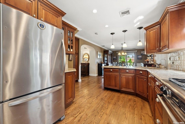 kitchen with ornamental molding, appliances with stainless steel finishes, decorative light fixtures, light hardwood / wood-style floors, and kitchen peninsula