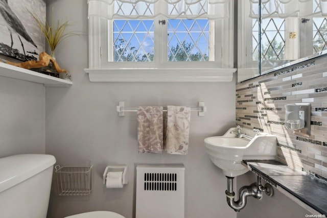 bathroom with backsplash, radiator heating unit, and toilet