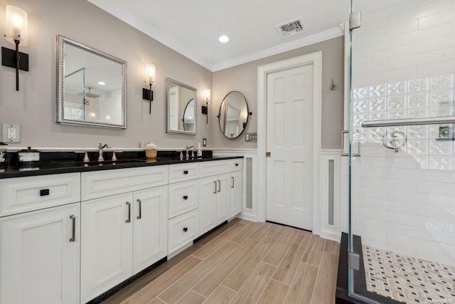 bathroom featuring hardwood / wood-style floors, vanity, a shower with door, and ornamental molding