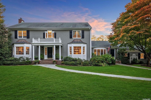 colonial house featuring a lawn and a balcony