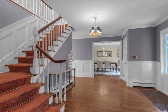 entrance foyer with dark hardwood / wood-style flooring, an inviting chandelier, ornamental molding, and a baseboard heating unit