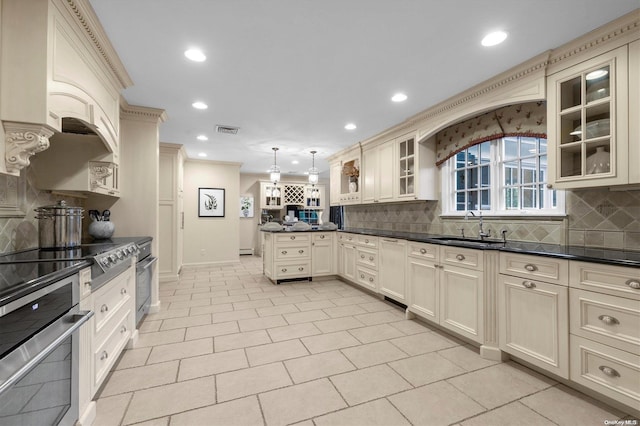 kitchen with sink, hanging light fixtures, stainless steel appliances, backsplash, and cream cabinets