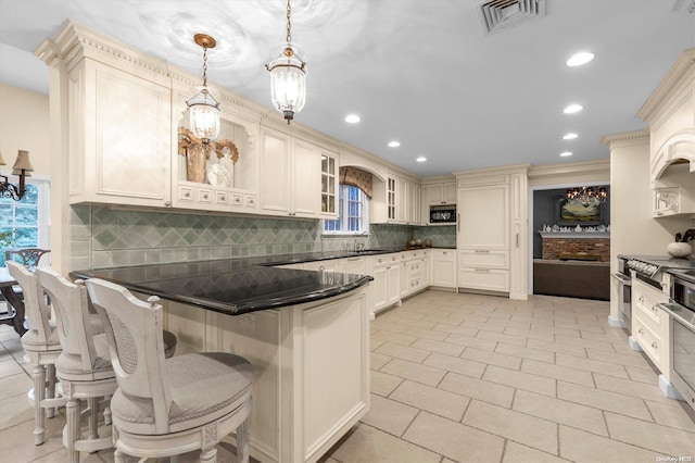 kitchen with sink, hanging light fixtures, tasteful backsplash, a breakfast bar area, and light tile patterned floors