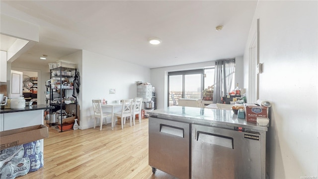 kitchen with white cabinetry, a peninsula, baseboards, and light wood finished floors