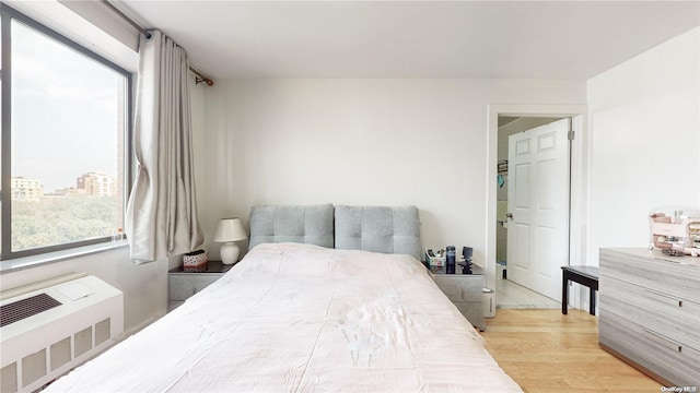 bedroom featuring multiple windows, radiator, and wood finished floors