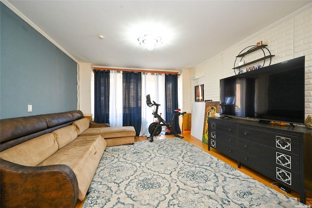 living room featuring crown molding, brick wall, and light hardwood / wood-style flooring