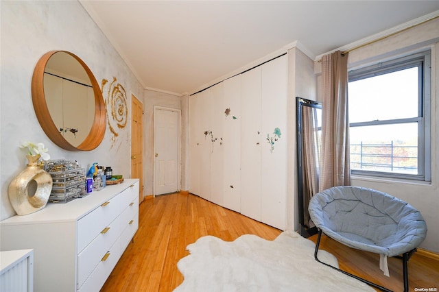 living area with ornamental molding and light hardwood / wood-style flooring