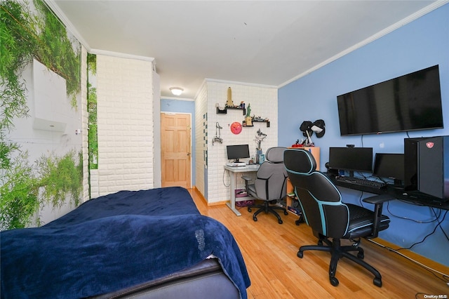 bedroom featuring ornamental molding, brick wall, and wood-type flooring