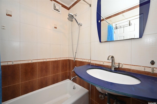 bathroom with tiled shower / bath, sink, and tile walls