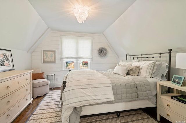 bedroom featuring dark hardwood / wood-style floors, wood walls, and vaulted ceiling