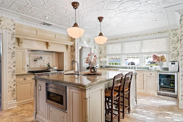 kitchen featuring a kitchen island with sink, sink, dark stone countertops, wine cooler, and hanging light fixtures