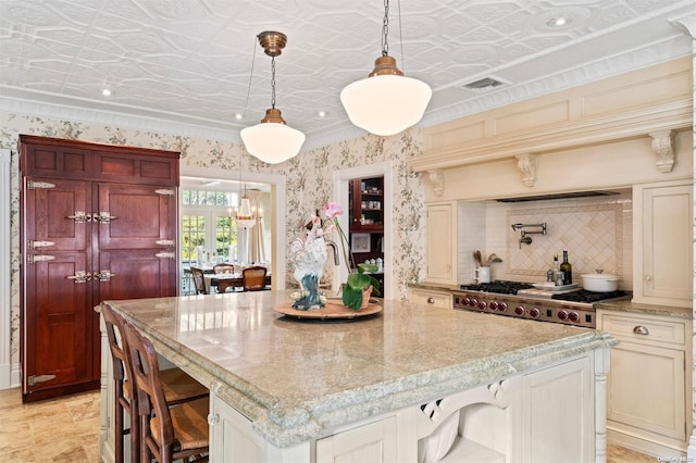 kitchen featuring a breakfast bar, cream cabinets, decorative backsplash, decorative light fixtures, and a kitchen island