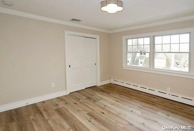 spare room featuring hardwood / wood-style flooring, ornamental molding, and a baseboard radiator