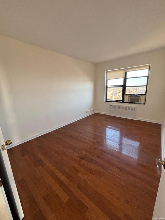 empty room with dark hardwood / wood-style flooring, radiator, and cooling unit