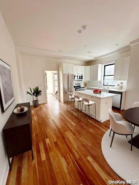 kitchen with white cabinets, a kitchen island, wood-type flooring, and stainless steel appliances