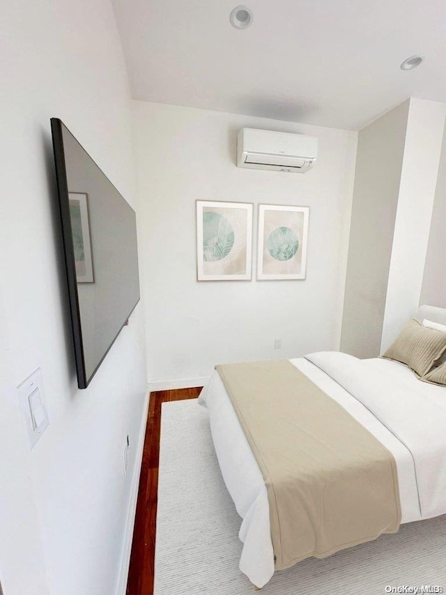 bedroom with wood-type flooring and an AC wall unit